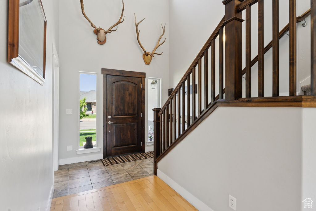 Foyer featuring stairs, healthy amount of natural light, baseboards, a towering ceiling, and wood finished floors
