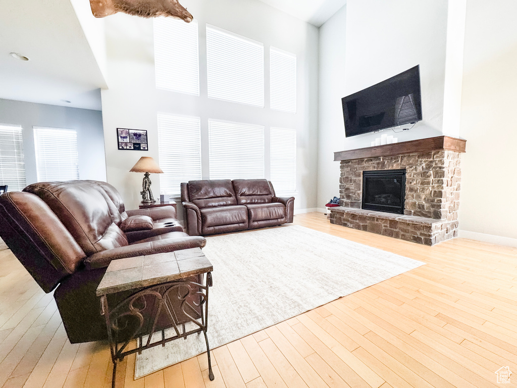 Living area featuring a high ceiling, hardwood / wood-style floors, a fireplace, and baseboards