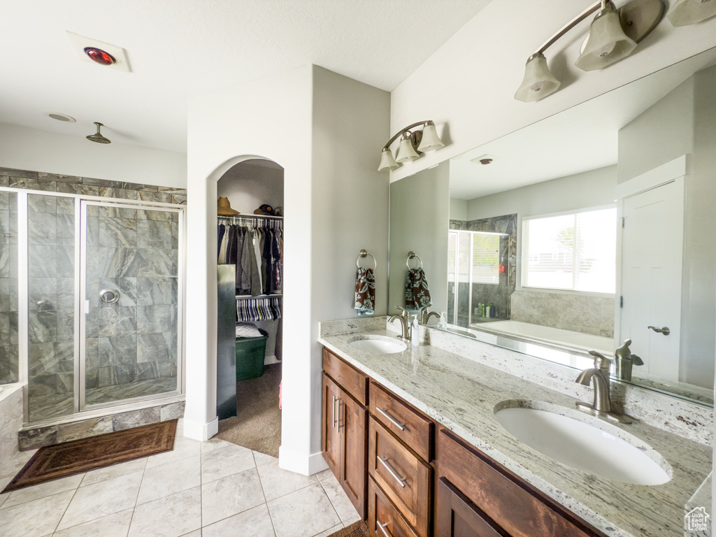 Full bath with a bath, a shower stall, double vanity, tile patterned floors, and a walk in closet