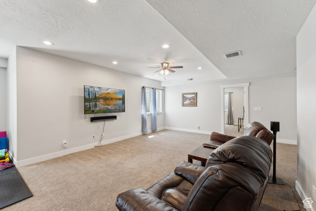 Carpeted living area featuring a textured ceiling, recessed lighting, ceiling fan, and baseboards