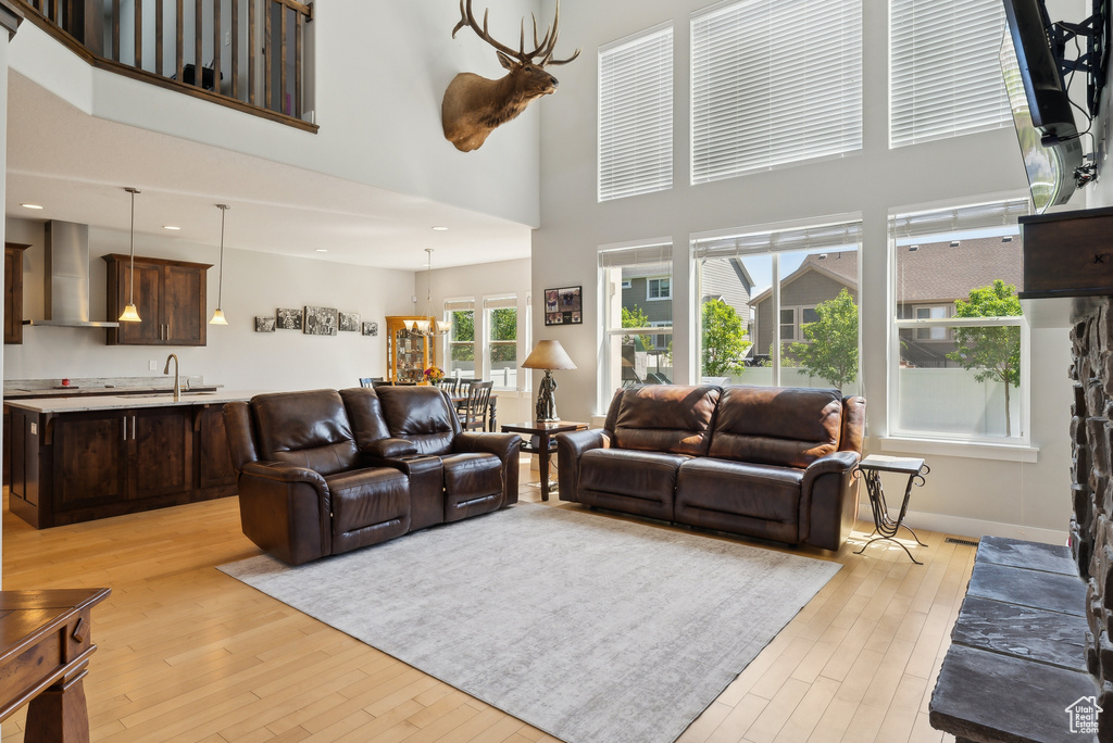 Living room with light wood-type flooring, a high ceiling, recessed lighting, and a chandelier