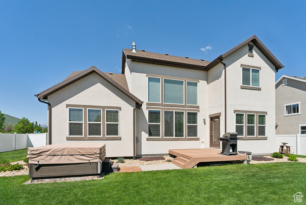 Rear view of house featuring a hot tub, a wooden deck, and stucco siding