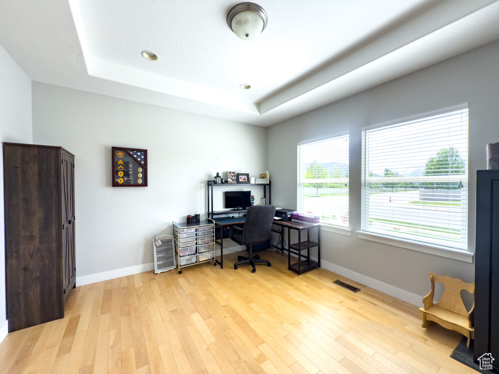 Office featuring a tray ceiling, baseboards, light wood-style floors, and recessed lighting