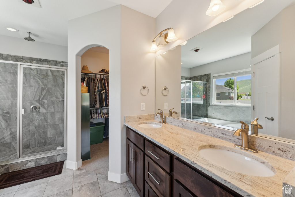 Full bathroom featuring a stall shower, a garden tub, double vanity, tile patterned flooring, and baseboards