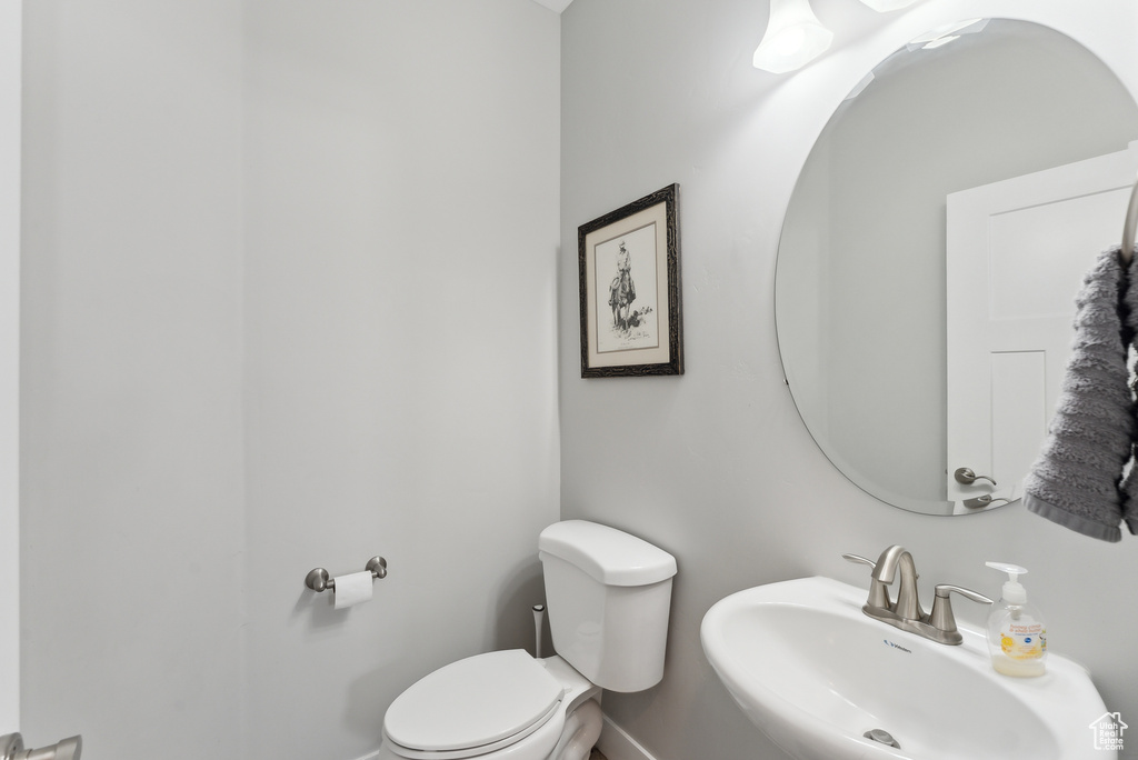 Bathroom featuring a sink, toilet, and baseboards