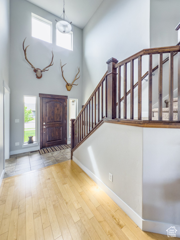 Entryway featuring a towering ceiling, baseboards, stairway, and plenty of natural light