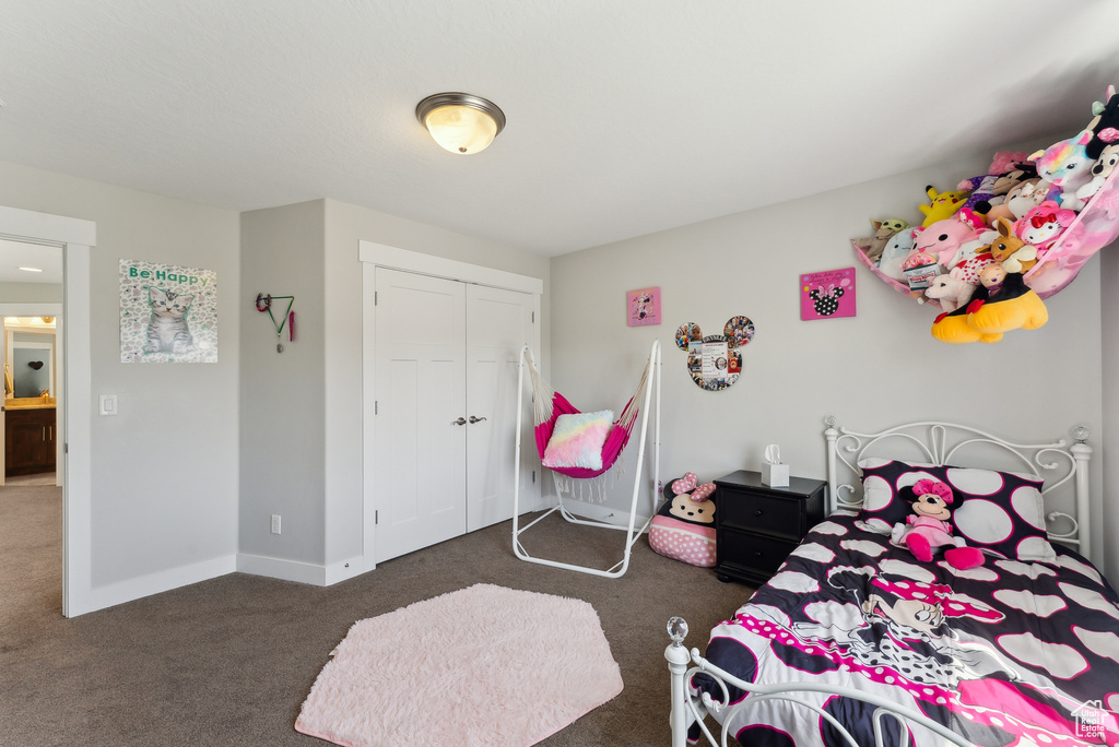 Carpeted bedroom with a closet and baseboards