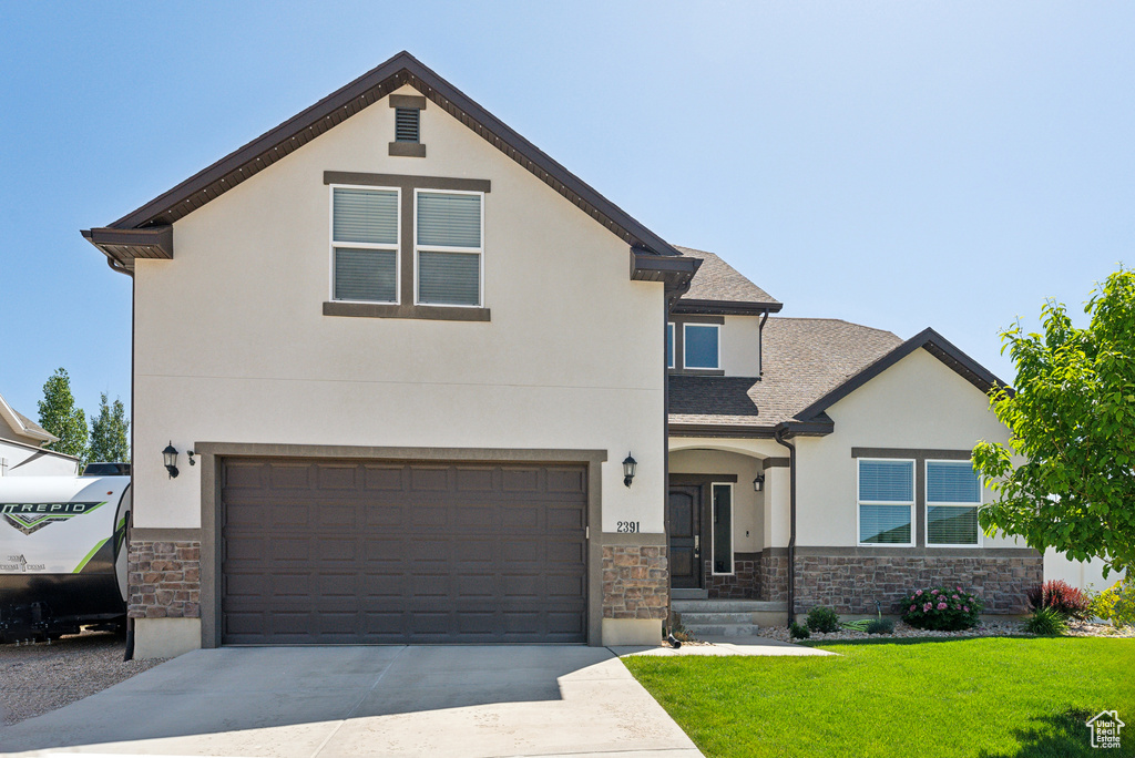 View of front of house featuring stone siding, stucco siding, a front lawn, concrete driveway, and a garage