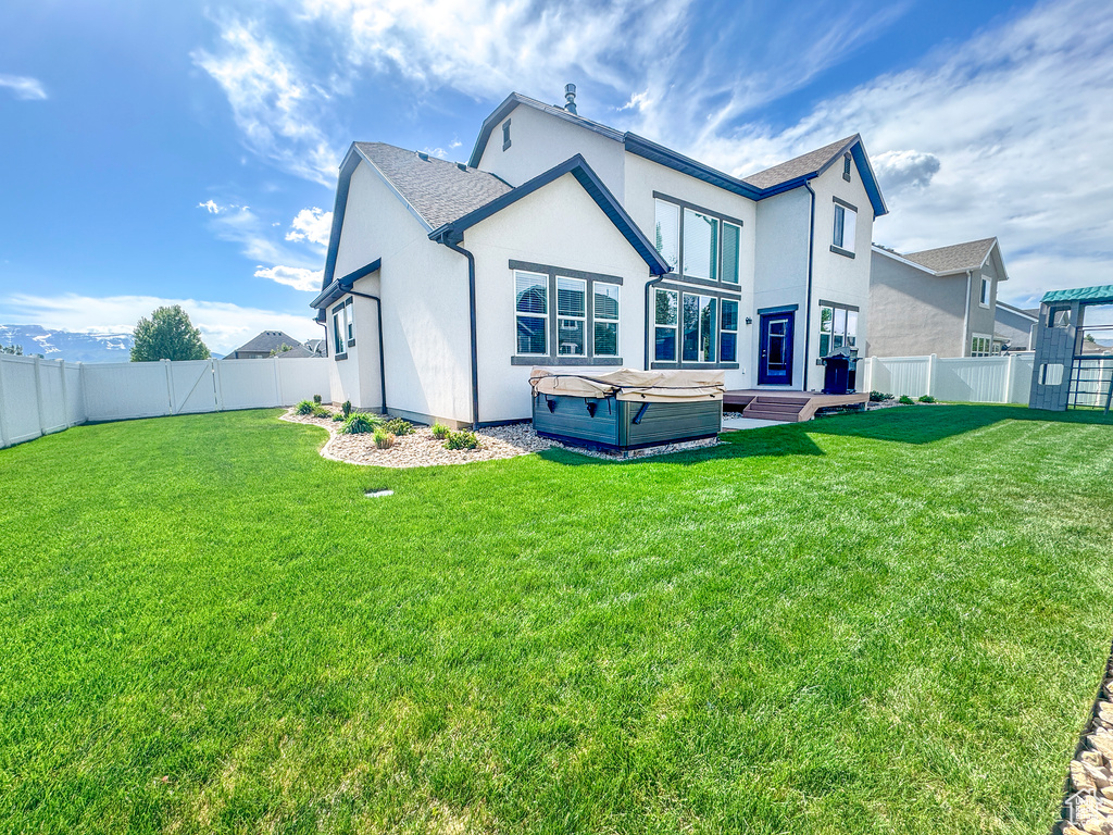 Rear view of property with a hot tub and stucco siding