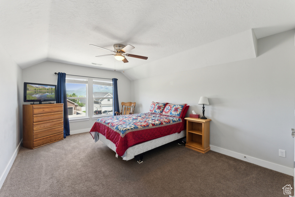 Carpeted bedroom with lofted ceiling, a textured ceiling, baseboards, and a ceiling fan