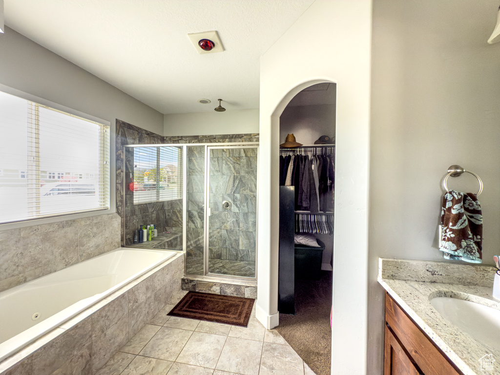 Bathroom with a stall shower, a garden tub, vanity, tile patterned flooring, and a spacious closet