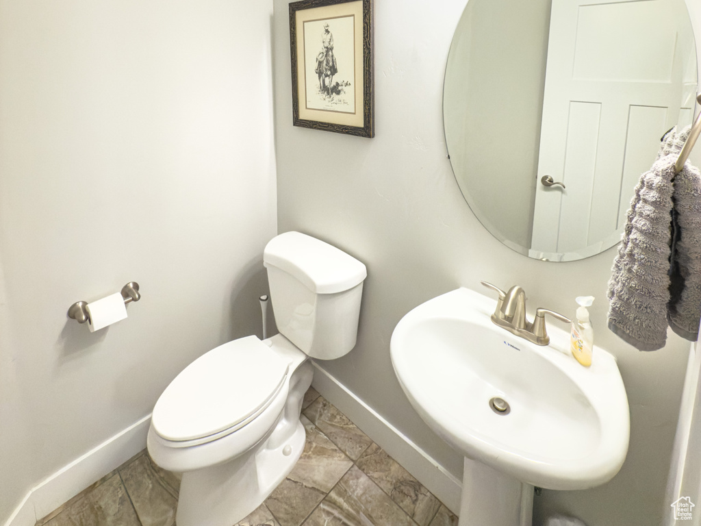 Bathroom featuring baseboards, toilet, and a sink