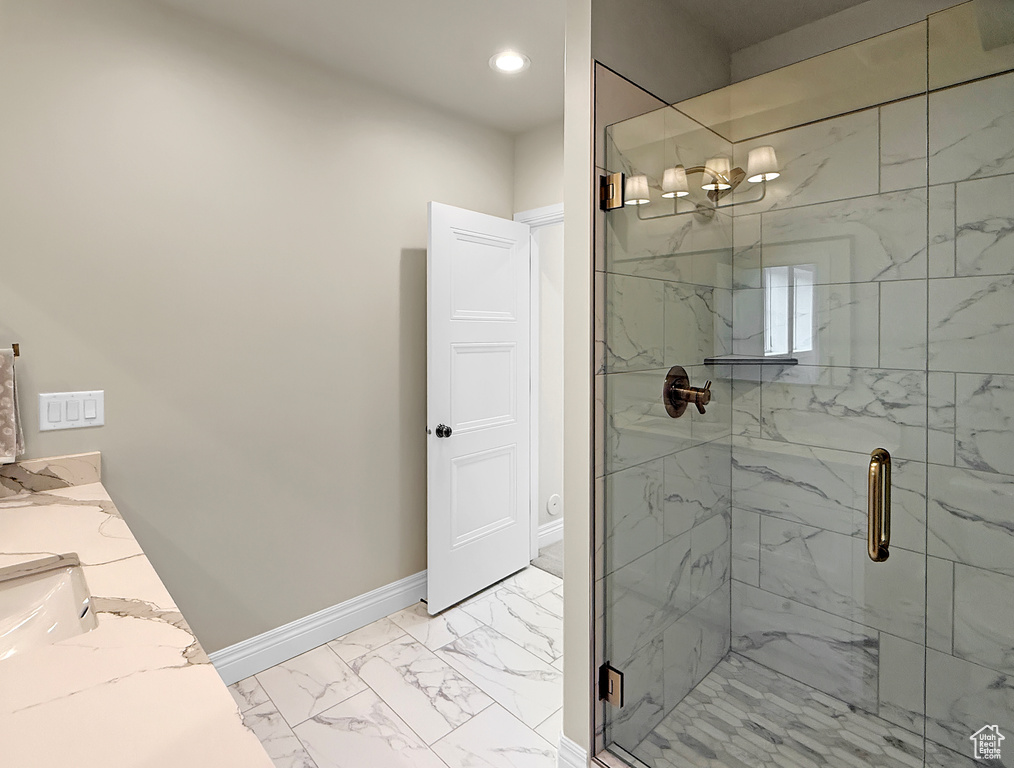 Bathroom with marble look tile flooring, a marble finish shower, a chandelier, baseboards, and recessed lighting