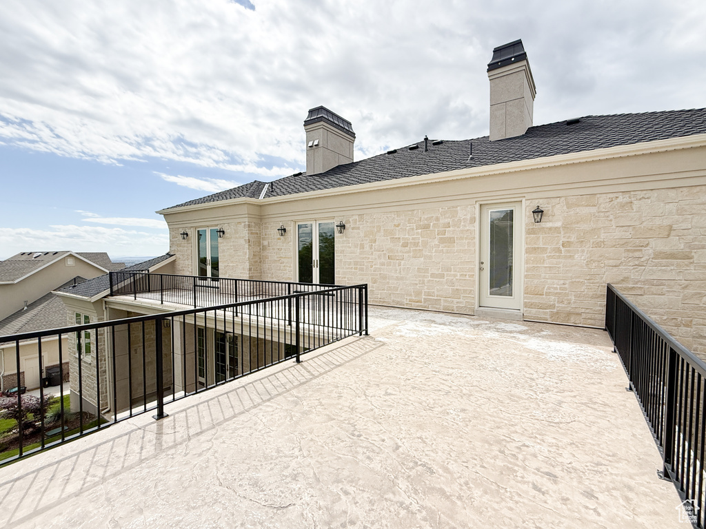 Rear view of house with a chimney, stone siding, and a patio area