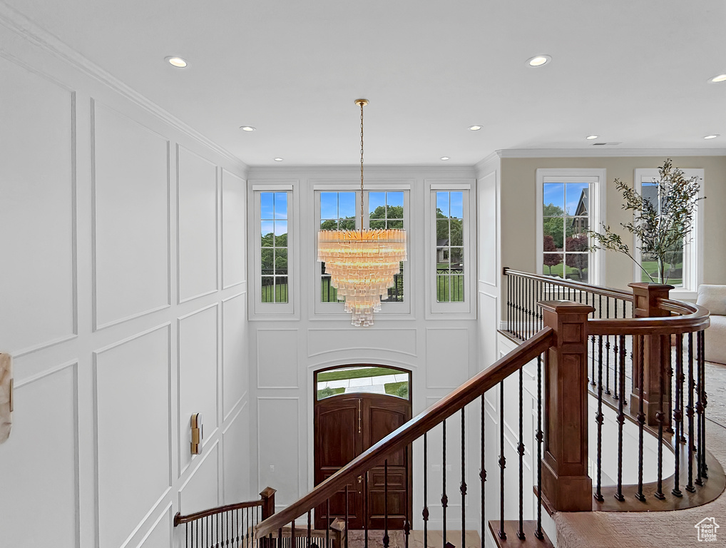 Stairs featuring a decorative wall, recessed lighting, crown molding, and a chandelier
