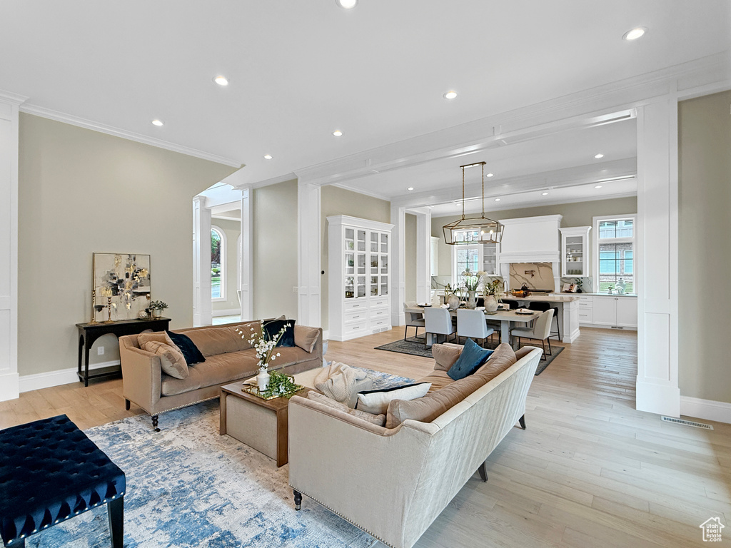 Living room with crown molding, recessed lighting, light wood-style floors, and baseboards
