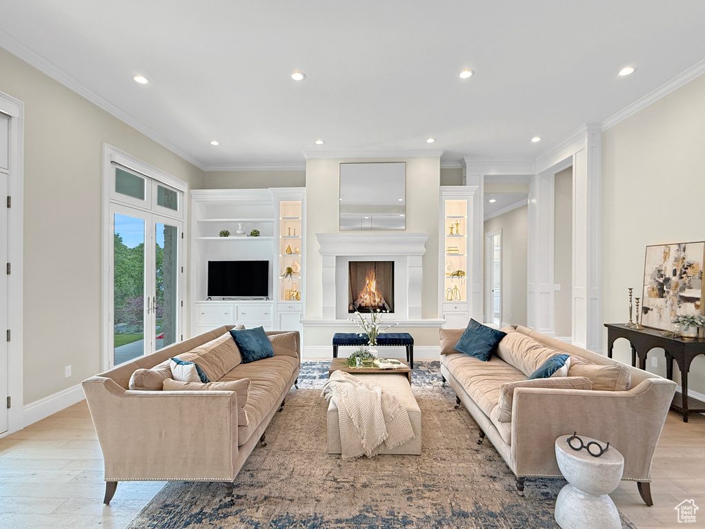 Living area with ornamental molding, recessed lighting, light wood finished floors, a warm lit fireplace, and baseboards