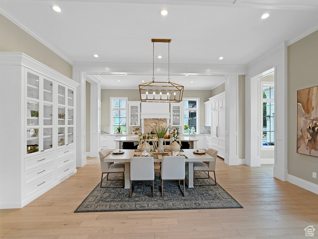Dining area with ornamental molding, light wood-type flooring, recessed lighting, baseboards, and a chandelier