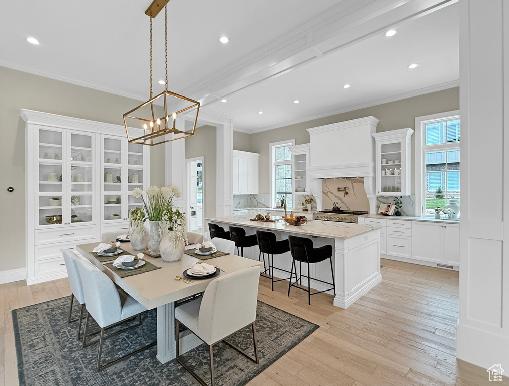 Dining area featuring crown molding, healthy amount of natural light, light wood-type flooring, a chandelier, and recessed lighting