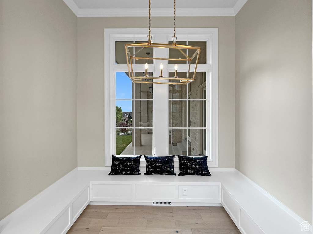 Unfurnished dining area with a chandelier, ornamental molding, and light wood-type flooring