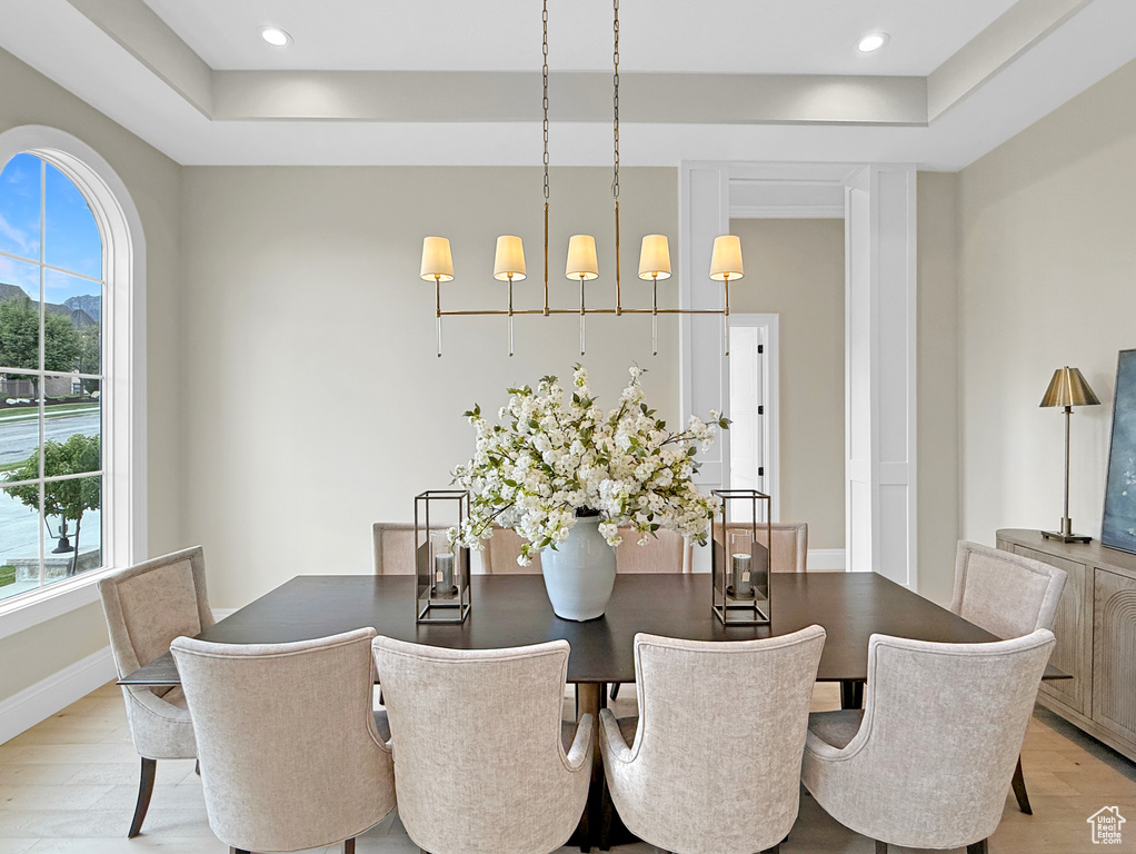 Dining space featuring plenty of natural light, light wood finished floors, a tray ceiling, recessed lighting, and baseboards