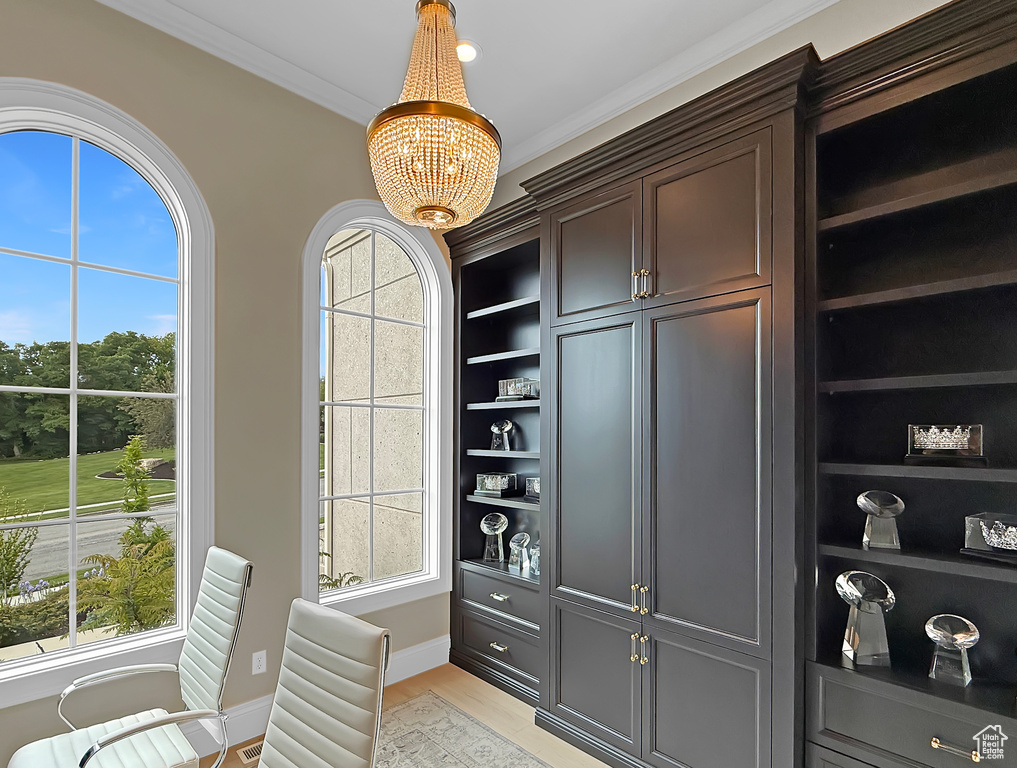 Walk in closet with a chandelier and light wood-style flooring