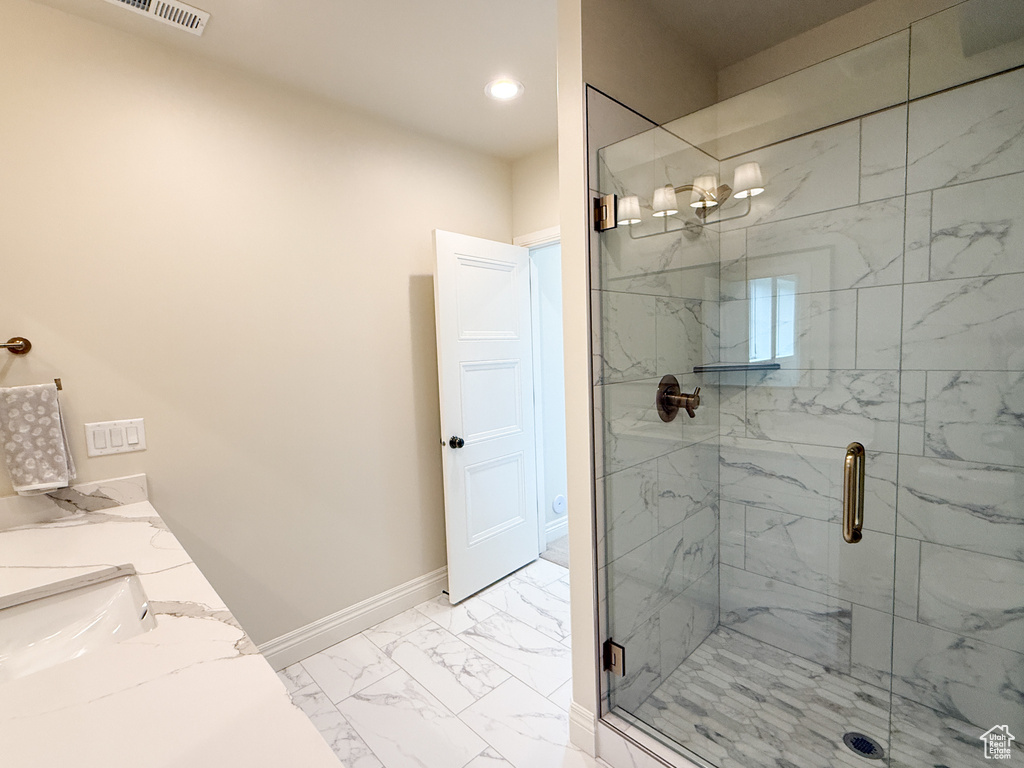 Full bathroom featuring marble look tile flooring, a marble finish shower, baseboards, recessed lighting, and double vanity