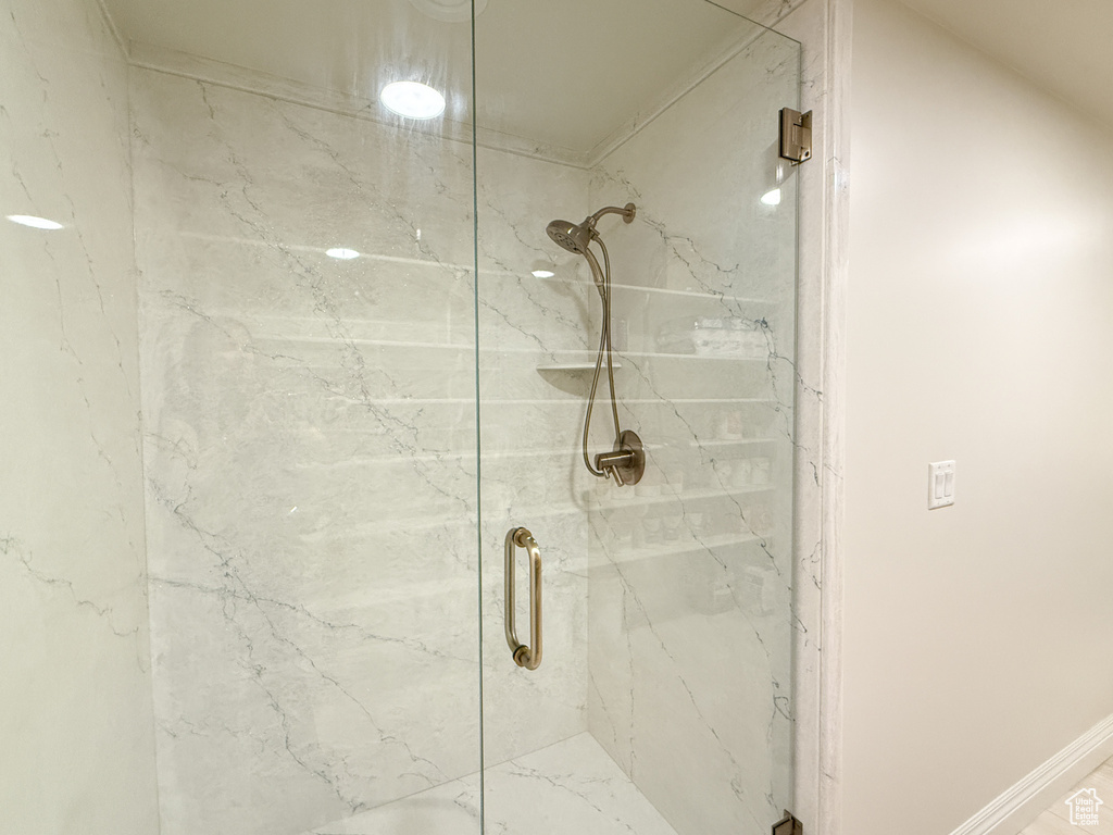 Bathroom with a marble finish shower and baseboards