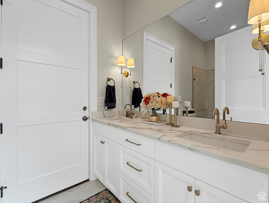 Bathroom featuring marble finish flooring, double vanity, recessed lighting, and a tile shower