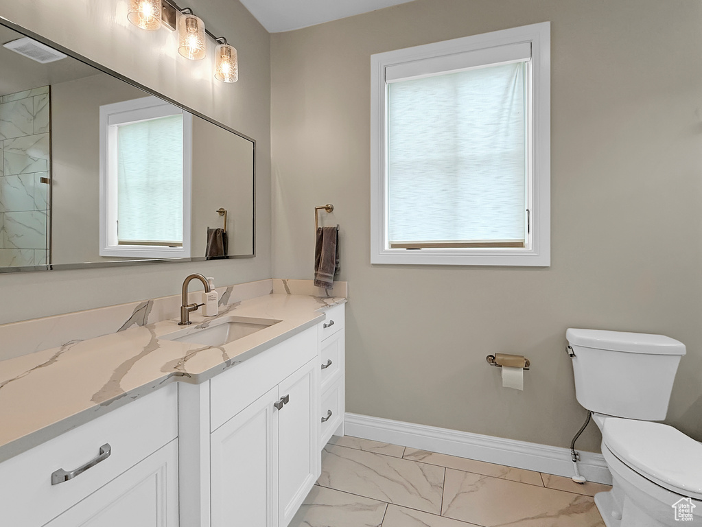 Full bathroom with marble finish floors, toilet, vanity, and baseboards