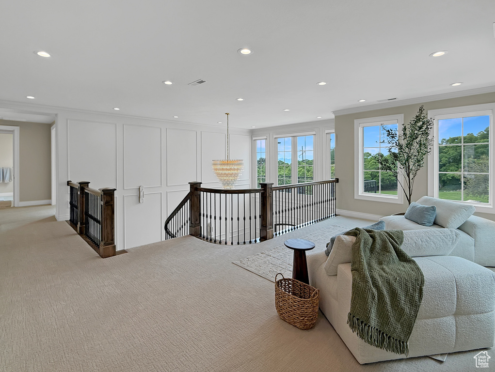 Sitting room with an upstairs landing, light colored carpet, recessed lighting, baseboards, and crown molding
