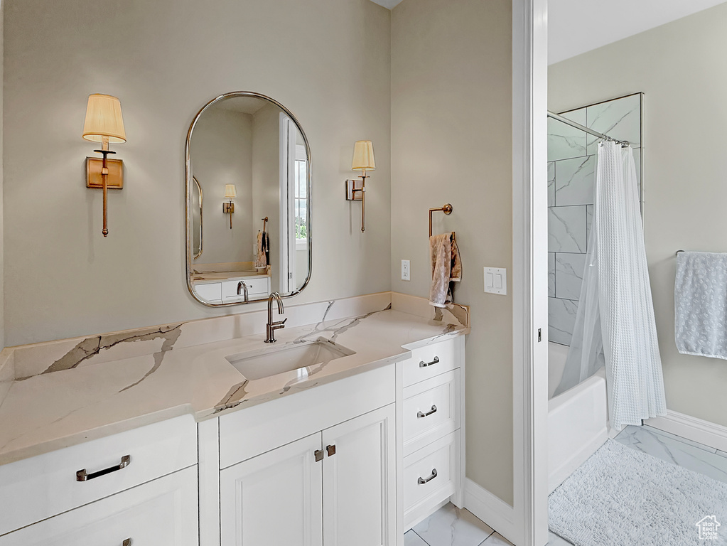 Bathroom featuring marble finish floors, vanity, baseboards, and shower / bath combination with curtain
