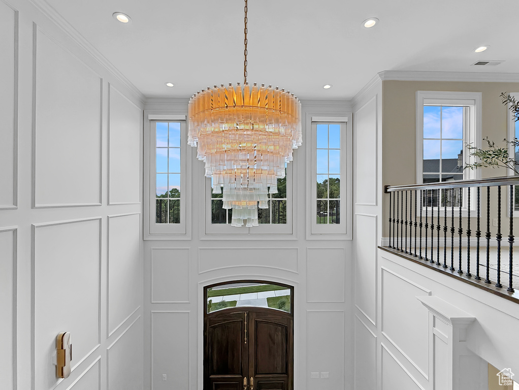 Detailed view of ornamental molding, a chandelier, recessed lighting, and a decorative wall