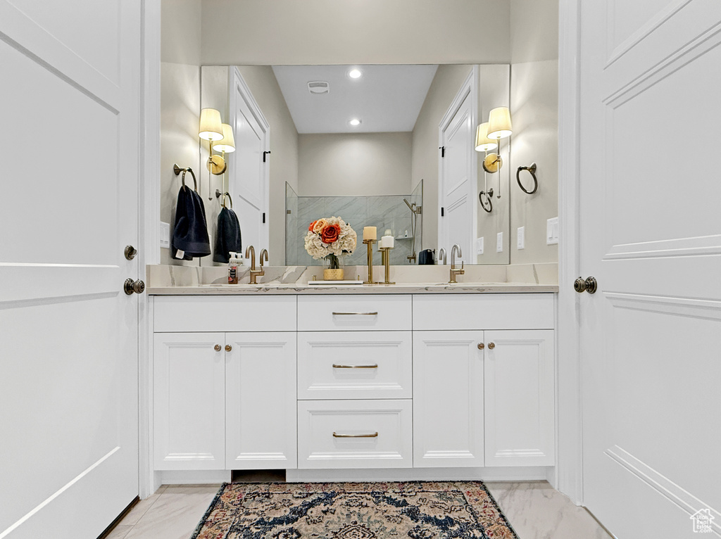 Full bathroom with marble look tile flooring, double vanity, a walk in shower, and recessed lighting