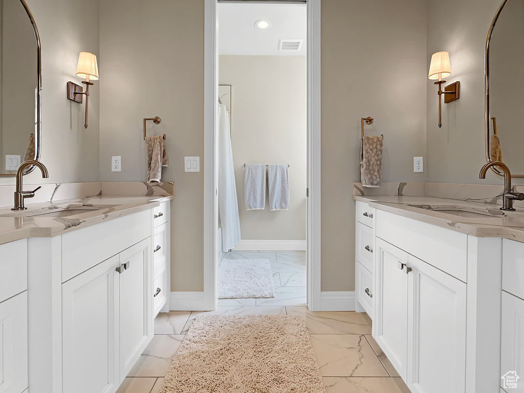 Bathroom with marble look tiles, baseboards, two vanities, recessed lighting, and a shower with shower curtain