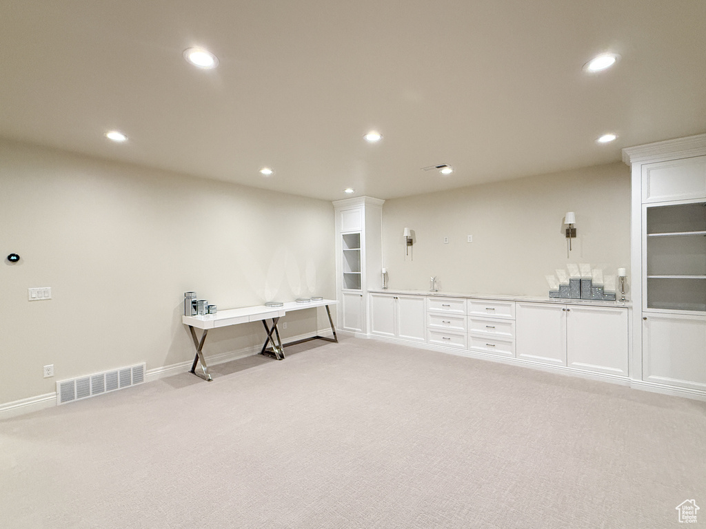 Unfurnished room featuring light carpet, recessed lighting, baseboards, and a sink