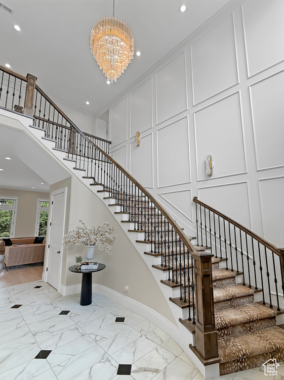 Staircase featuring a decorative wall, marble finish flooring, a chandelier, baseboards, and recessed lighting
