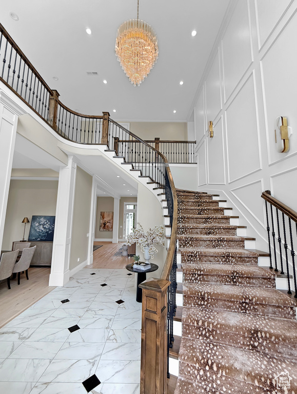 Stairs with marble finish flooring, a chandelier, recessed lighting, baseboards, and a high ceiling