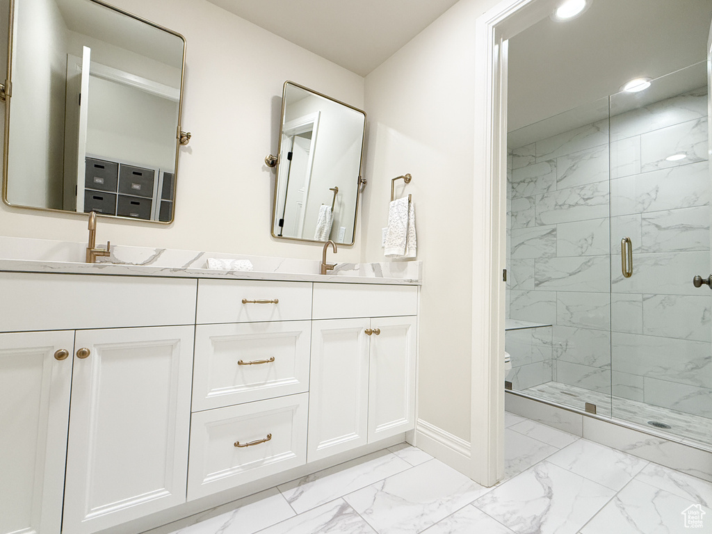 Bathroom with marble finish flooring, double vanity, a marble finish shower, toilet, and baseboards