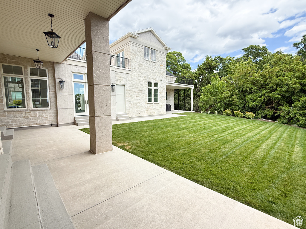 View of green lawn with a balcony and a patio
