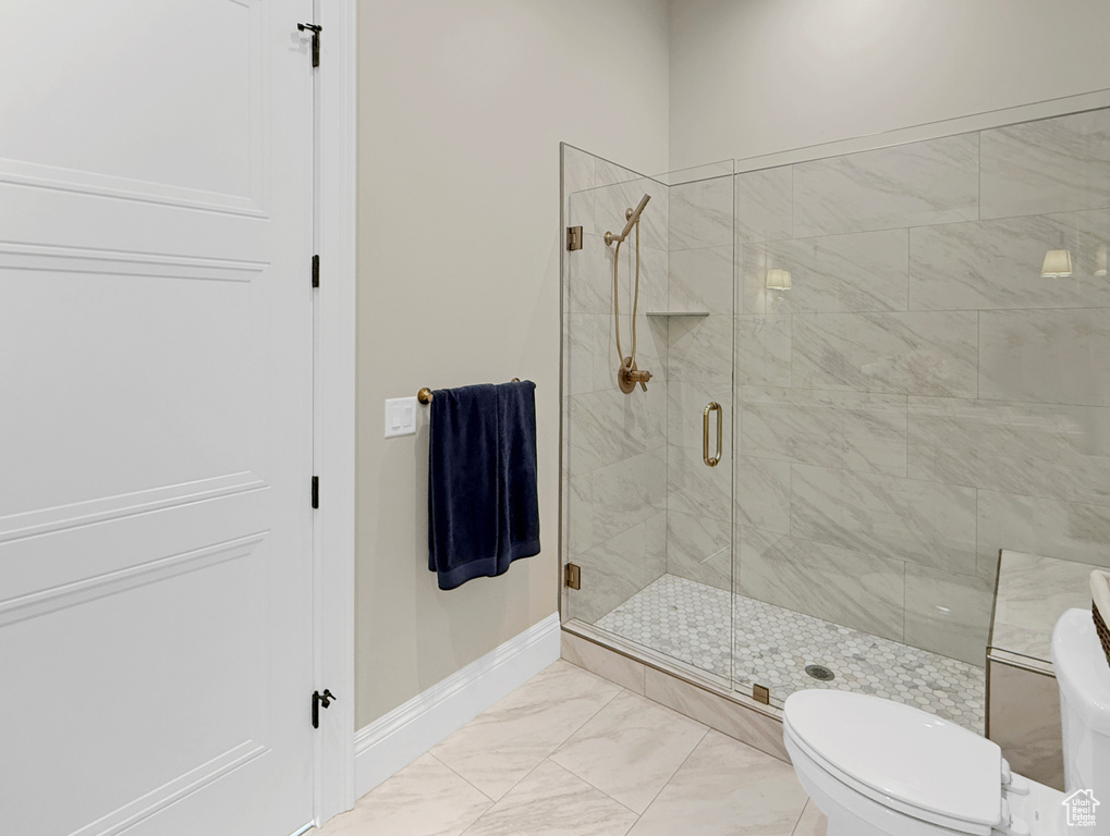 Bathroom with baseboards, a shower stall, toilet, and marble finish flooring