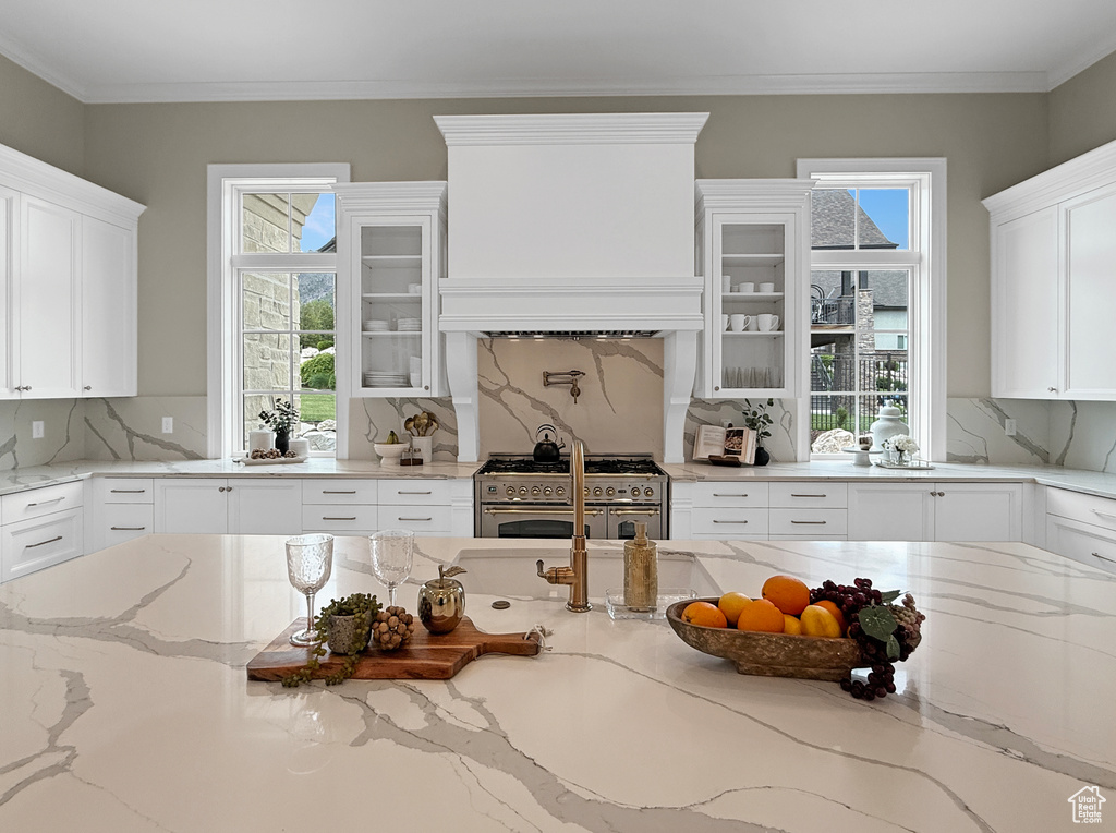 Kitchen featuring range with two ovens, white cabinets, decorative backsplash, and crown molding