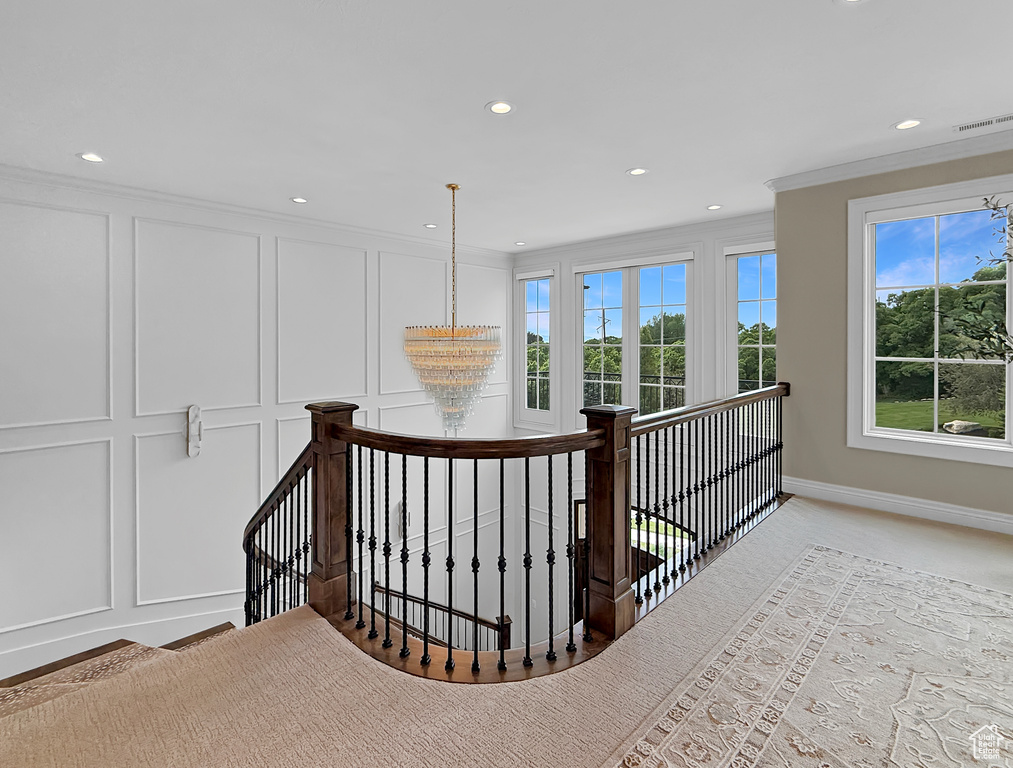 Hall with an upstairs landing, a decorative wall, recessed lighting, ornamental molding, and baseboards