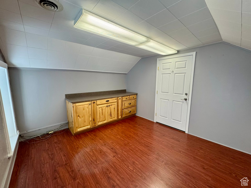 Additional living space featuring vaulted ceiling and dark wood-type flooring