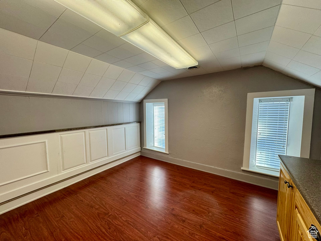 Additional living space with lofted ceiling, dark wood-style flooring, and baseboards