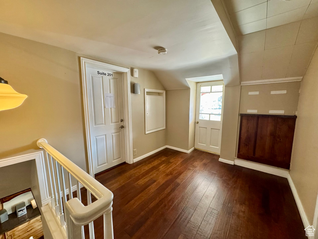 Foyer featuring dark wood-style floors, baseboards, and vaulted ceiling