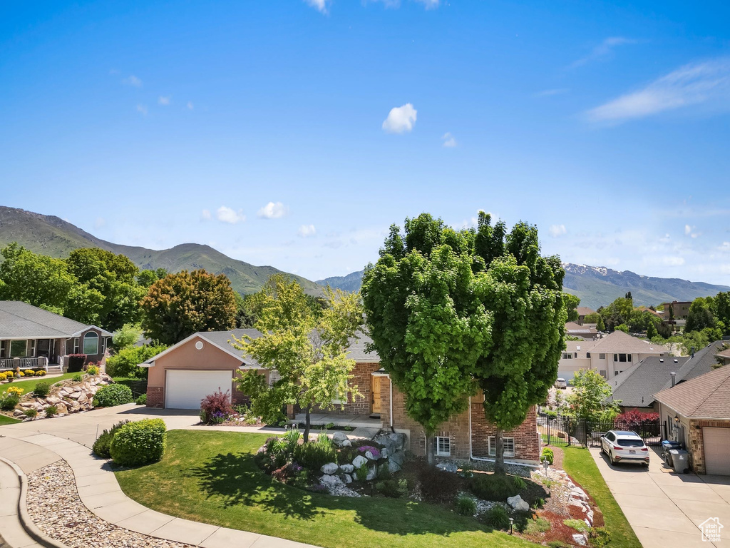 View of front of property with brick siding, a mountain view, concrete driveway, and a garage