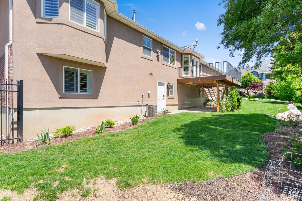 Back of property with a wooden deck, stairs, and stucco siding