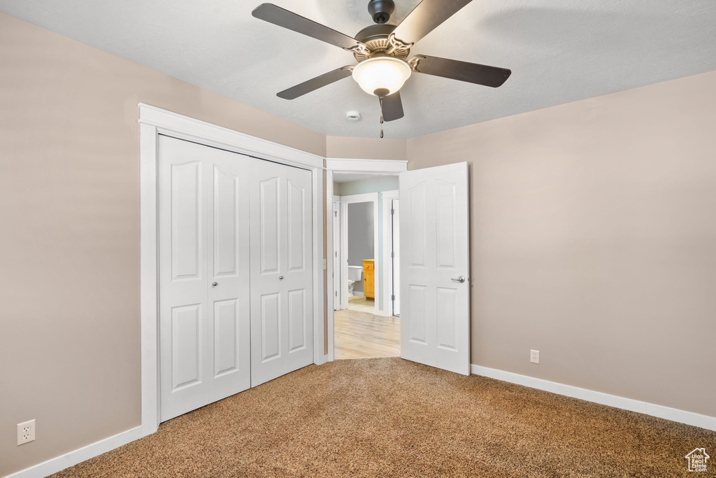 Unfurnished bedroom with carpet, baseboards, a closet, and ceiling fan