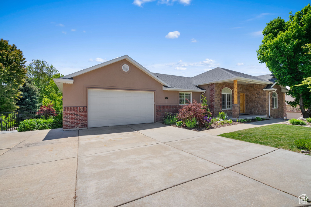 Ranch-style home featuring brick siding, a garage, driveway, and roof with shingles